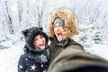 Fototapeta na wymiar Season and relationship concept - Funny couple taking selfie in the winter time