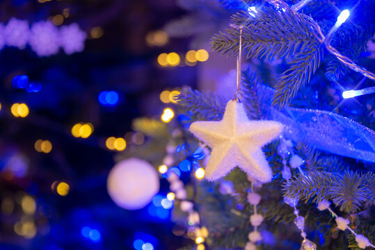 White Star Hanging On A Christmas Tree, Christmas Ornaments At Night, White And Gold Holiday Lights