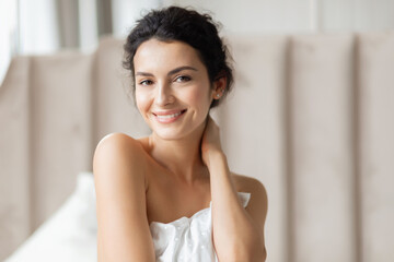 Fototapeta na wymiar Beautiful woman close up portrait indoor. Charming female posing with white pillow in bed headshot