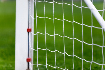White Soccer Goal Post and Net. Grass Field in Blurred Background