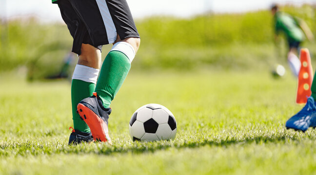 Closeup Image of soccer player legs and soccer ball on the field. Fotballers on practice training lesson. Youth athletes on soccer outdooe training