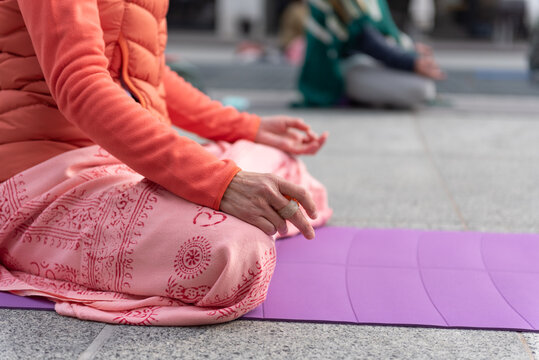 Yoga teachers protesting against the blockade and restrictions of Covid-19 in a square in Brescia, Italy. Shot of the hands resting on the knees of the crossed legs. People are meditating.