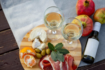 picnic with wine prosciutto, cheese, olives, lies on a gray blanket, next to ripe pomegranates. Close up