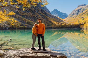 Happy couple at crystal lake in the autumnal mountains. Mountain lake and hikers couple