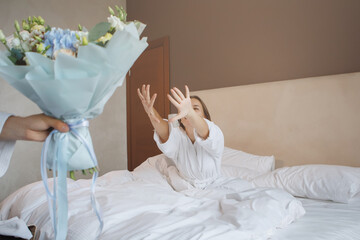 A woman in bed with a bouquet of flowers.