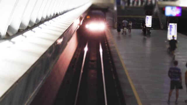 Underground train arrives at russian subway station and departures. People are waiting for arrival of metro. Passengers get out and boarding a carriages. Public transportation. Tilt-Shift effects