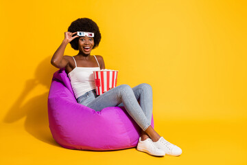 Photo of surprised impressed young lady wear casual outfit arm 3d glasses sitting beanbag popcorn bucket isolated yellow color background