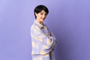 Woman with short hair isolated on purple background looking to the side and smiling
