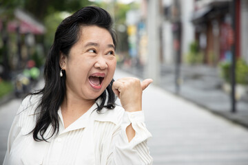 Excited old asian senior woman giving yes, ok, approving thumb up gesture