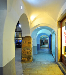 
A picturesque street with arcades and small shops at night in the historic center of Évora,...