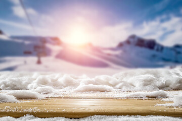 Snow on a wooden table in alpine mountain surroundings on a beautiful winter day