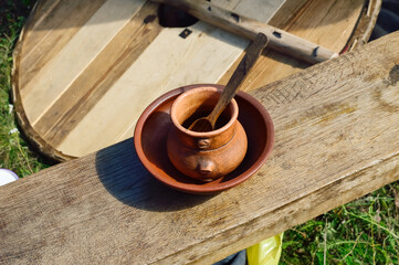 close-up - a clay cup and a plate with a spoon stand on a wooden board