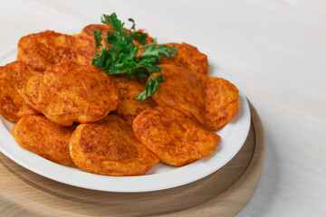 Pumpkin cutlets. Vegetable burgers on a white plate on a light wooden background. Close-up.