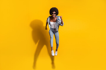 Fototapeta na wymiar Photo of purposeful young woman wear casual jeans clothes jumping high running isolated yellow color background