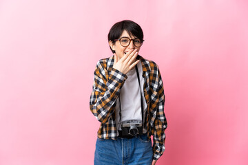 Young photographer woman isolated on pink background happy and smiling covering mouth with hand