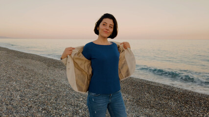 Ragazza con maglia blu e giacca marrone passeggia in riva all'oceano