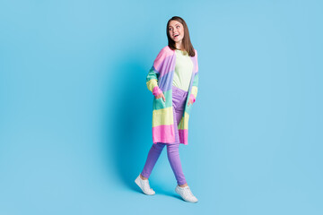 Full length photo of positive smiling lady wear casual colorful outfit hands arms pockets looking back empty space isolated blue color background