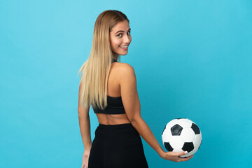 Young blonde woman isolated on blue background with soccer ball