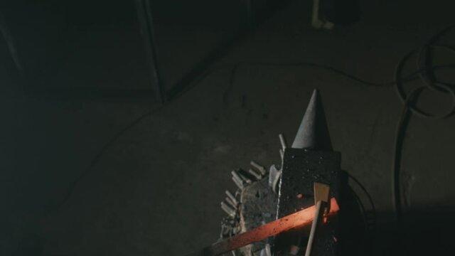 Forge workshop. Smithy manual production. Hands of smith with hammer hit on glowing hot metal, on the anvil, the forging process. Blacksmith makes iron products for manufacture of fireplace, stove.