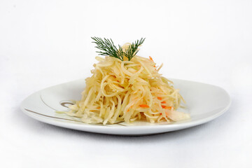 Salad from fresh cabbage, carrots and dill on a white plate isolated on a white background