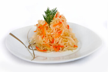 Mixed salad of home sauerkraut with carrots and spices on a plate isolated on a white background.