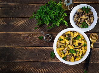 Fusilli pasta gluten free with forest mushrooms on a white plate. Vegetarian / vegan  food. Italian cuisine. Top view, flat lay, copy space