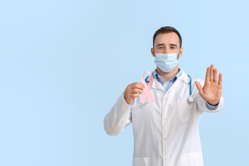 Fototapeta na wymiar Doctor in medical mask and with pink ribbon on color background. Breast cancer awareness concept