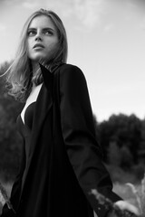 Naklejka premium Young beautiful girl walking. Summer landscape,good weather. Beach, sea. Windy day with sun and clouds. Cotton black dress eco style. Nature and freedom. Follow me. Long hair, big eyes and lips