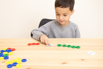 Preschool child plays a math game, interested, focused. Topic of comparing numbers, concepts of more than, less than, equal to that, smart boy. Little genius of mathematics. Caucasian. Copy space.