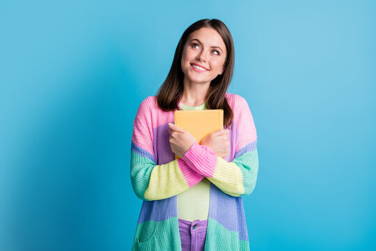 Photo of happy dreamy young woman look empty space hold favourite book isolated on blue color background
