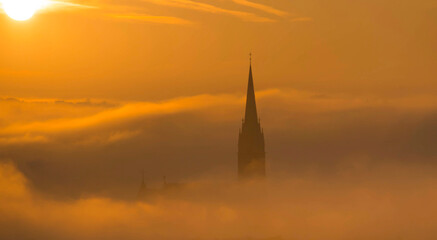 Church of the Sacred Heart of Jesus surrounded by fog and clouds, in Graz, Styria region, Austria, at sunrise. Beautiful foggy morning over the city of Graz, in autumn