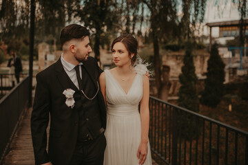 Fototapeta premium Bride and groom in a park kissing.couple newlyweds bride and groom at a wedding in nature green forest are kissing photo portrait.Wedding Couple