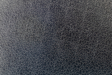 Macro photo of black artificial leather with a special print in the form of scales or irregular islets.