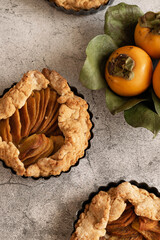 Ready to eat sweet pie with persimmons on grey cement background