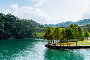 Fototapeta premium Sun Moon Lake, Yuchi Township, Nantou County, Taiwan, 2019, Oct 14th - A couple sitting on a bench looking at the lake view.
