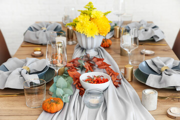 Beautiful table setting with pumpkins and autumn leaves in dining room