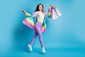 Full body photo of attractive positive shopper jumping arms flying wear trousers isolated on blue...