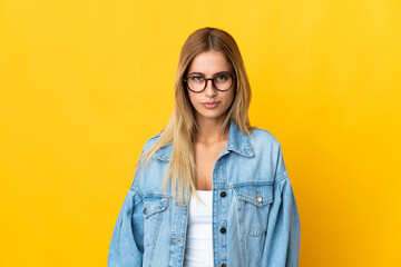Young blonde woman isolated on yellow background with sad expression