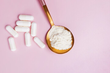 Collagen or protein powder in a spoon and white capsules