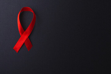 Red bow ribbon symbol HIV, AIDS cancer awareness with shadows, studio shot isolated on black background, Healthcare medicine concept, World AIDS Day