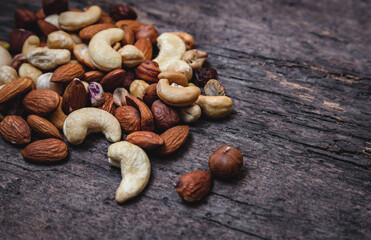 Nuts on a wooden background. Various types of nuts such as hazelnuts, almonds, walnuts and pistachios are scattered on a wooden background. Top view