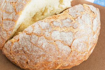 Round fresh white bread cut into two pieces is on a brown background