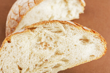 A slice of white fresh crispy bread on a brown background