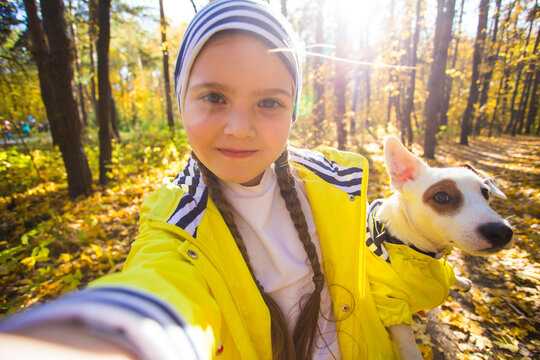 Child taking selfie with dog jack russell terrier. Autumn walk with a dog, children and pet concept.