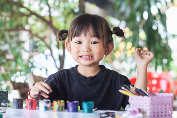 Asian student drawing and painting colours on the paper in the room. Study​ from​ home,...