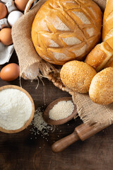 Wheat round bread. Wheat bread is surrounded by baking ingredients. Bread close-up. Eggs, salt, flour, seeds on the kitchen table