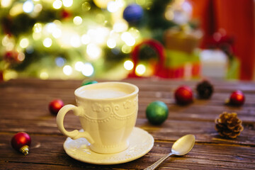 Mug with hot chocolate on a wooden table with Christmas decorations on a background of the Christmas tree