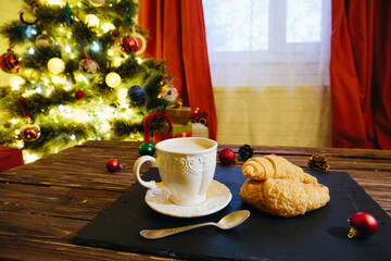 Mug with hot chocolate on a wooden table with Christmas decorations on a background of the Christmas tree