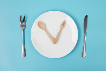 Top view white ceramic plate with knife, spoon and fork on blue background. Intermittent fasting, Ketogenic dieting, weight loss, meal plan and healthy food concept