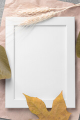 Empty white picture frame with natural leaves 